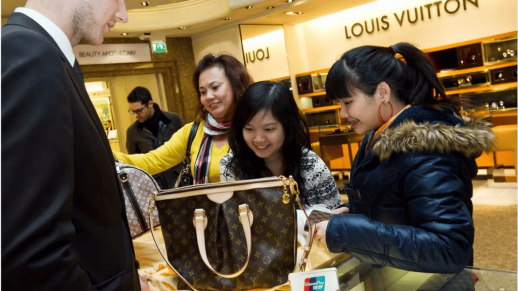 Women browsing luxury handbags in a store, highlighting luxury shopping trends.